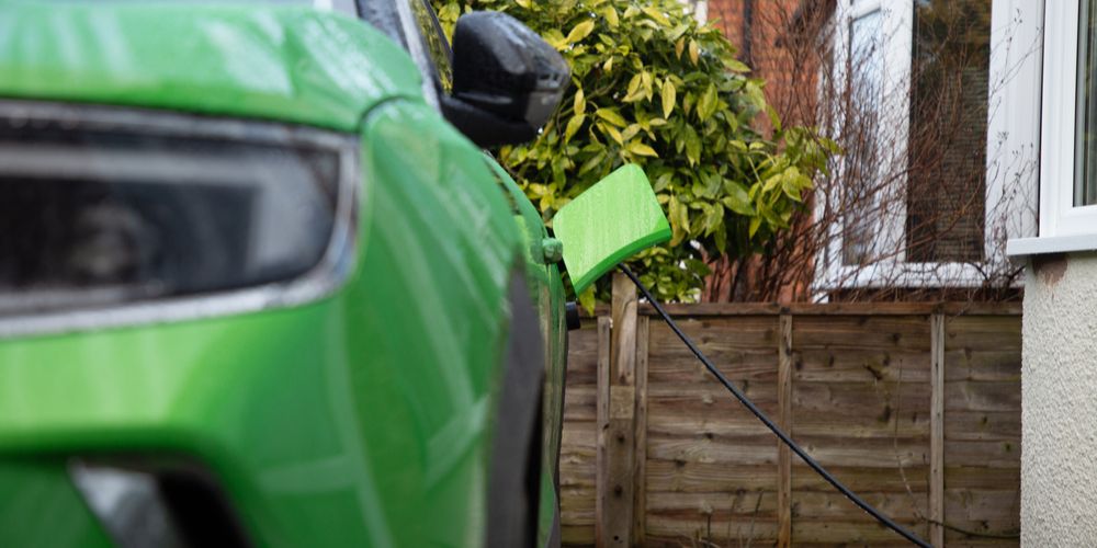 A green-coloured EV charges at home